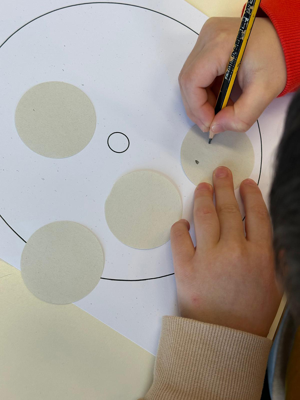 Bambino che si appresta a disegnare cerchio con varie facce con emozioni differenti
